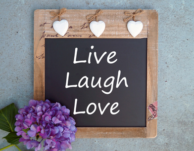 Photo of blackboard with hanging hearts & the words Live, laugh, love.