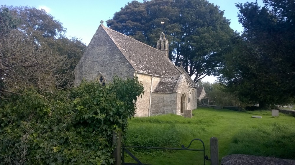 Photo of All Saint's Shorncote beyond a gate.