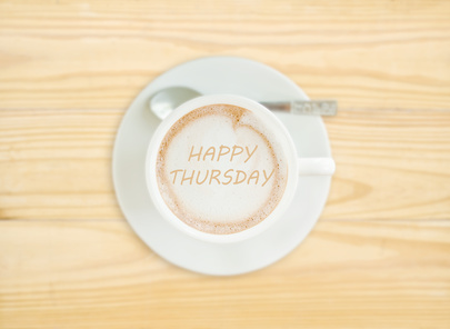 Photo of a cup of Cappucino coffee with the words 'Happy Thursday' written in the coffee