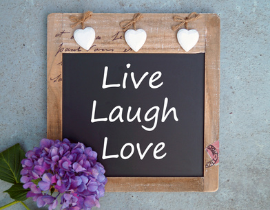 Photo of blackboard with hanging hearts & the words Live, laugh, love.